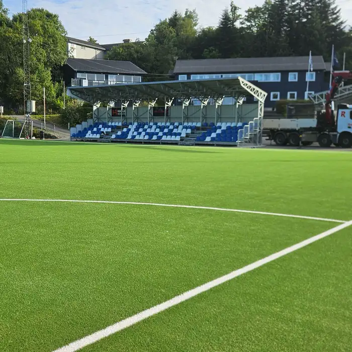 Kunstgressbane med tribune og oppmerket sidelinje.